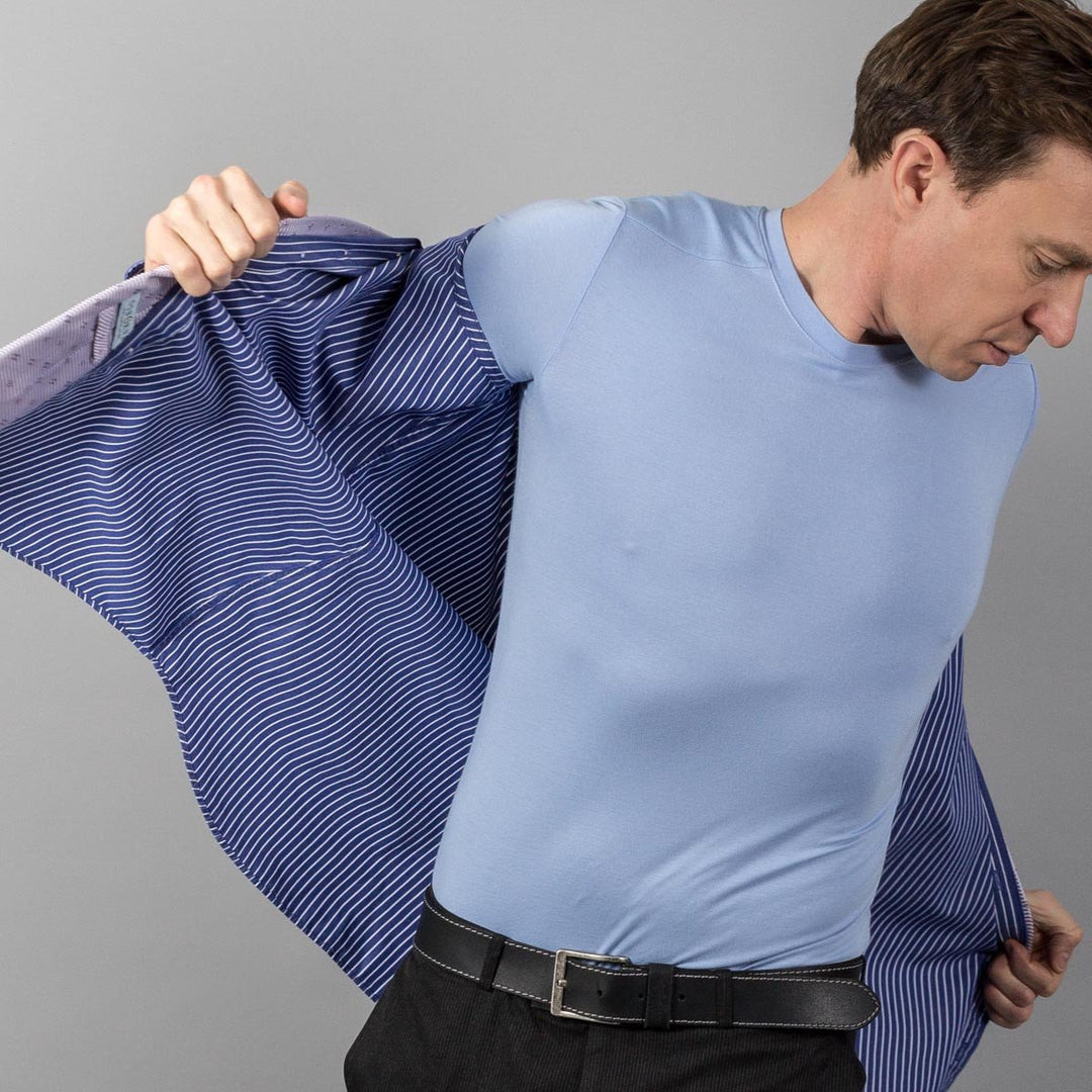 Man in light blue crew neck undershirt putting on shirt
