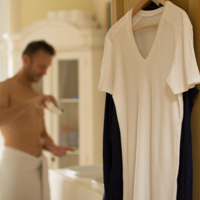 Man in bathroom with undershirts hanging on door