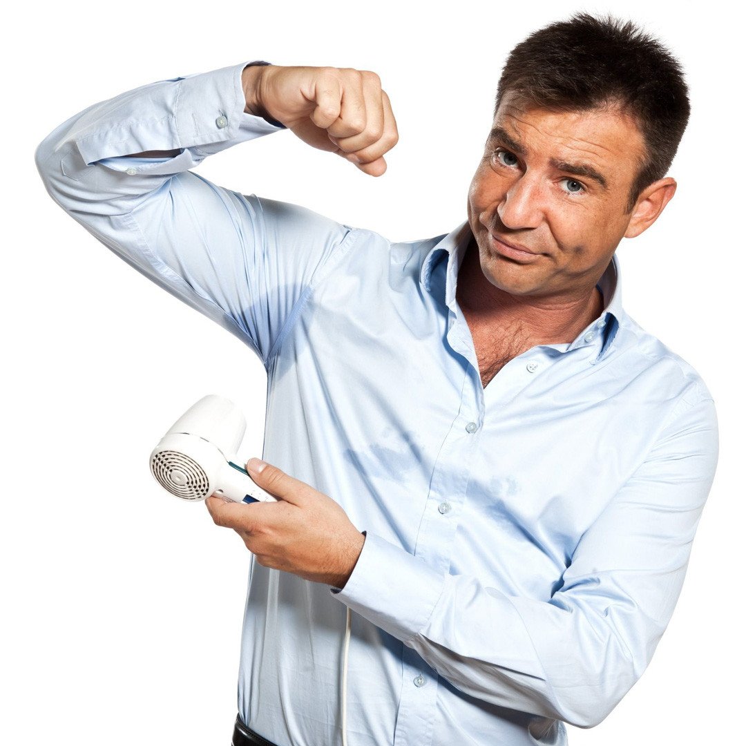 Man drying sweat marks on shirt with a hair dryer