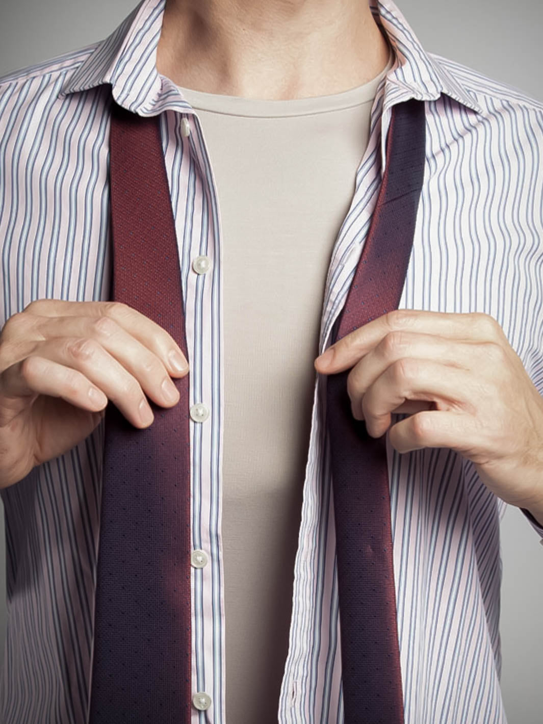 Man wearing crew neck undershirt in heather grey under a pink shirt and tie open to show the undershirt